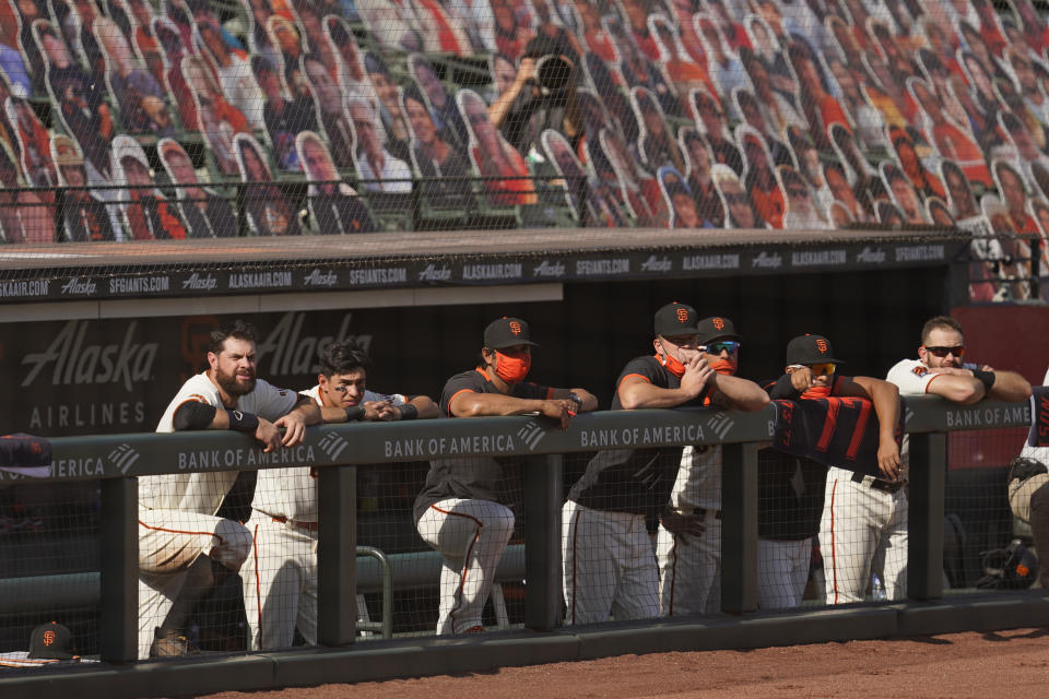 The San Francisco Giants, including Brandon Belt, left, and Mauricio Dubon, second from left, watch the final moments of a baseball game from the dugout in the ninth inning against the San Diego Padres, Sunday, Sept. 27, 2020, in San Francisco. (AP Photo/Eric Risberg)