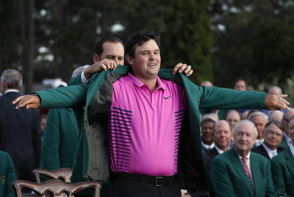 Sergio Garcia of Spain (rear), last year’s Masters champion, helps put the green jacket on 2018 Masters winner Patrick Reed on Sunday. (REUTERS)