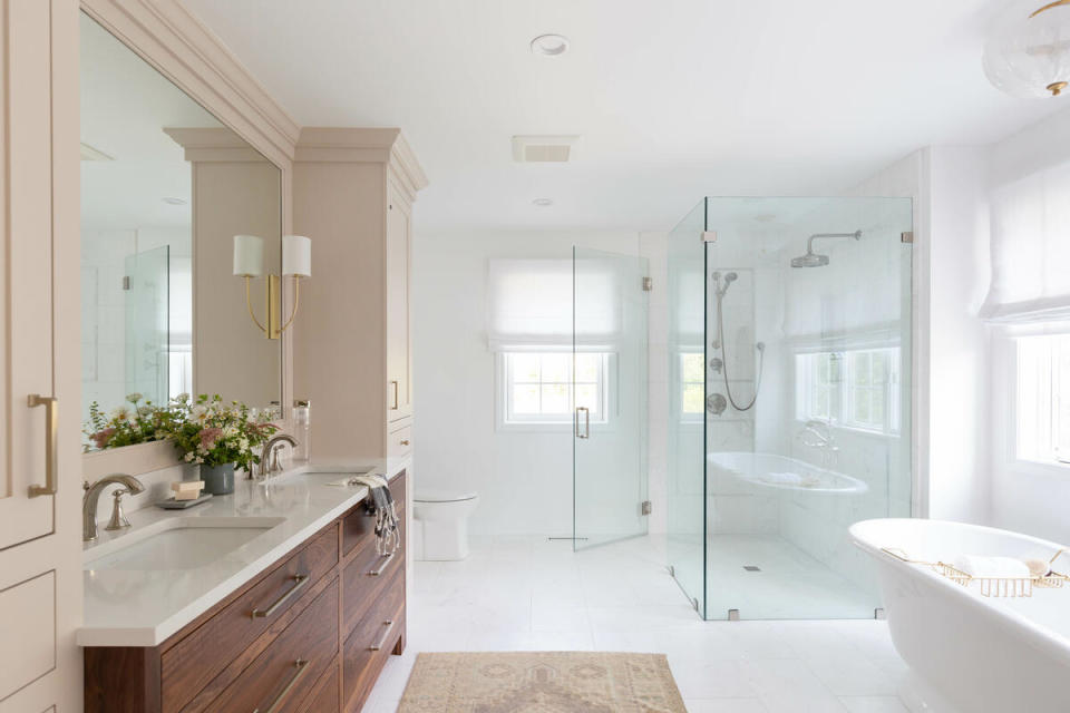 In an expansive bathroom, an double vanity is bookended by buff-hued built-ins for extra storage