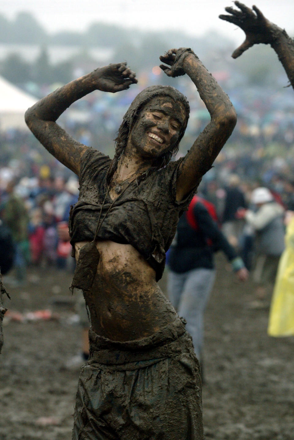 Music-lovers dance soaked in mud in front of the Pyramid stage in 2004.