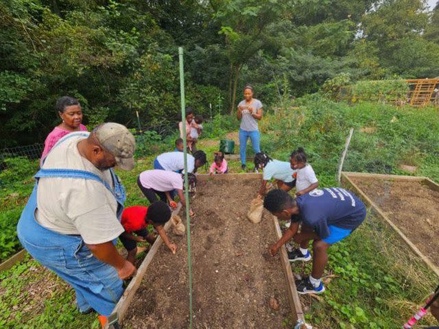 <p>Courtesy Chris Battle</p> Adults teaching local kids about planting vegetables at Battlefield Farm & Garden
