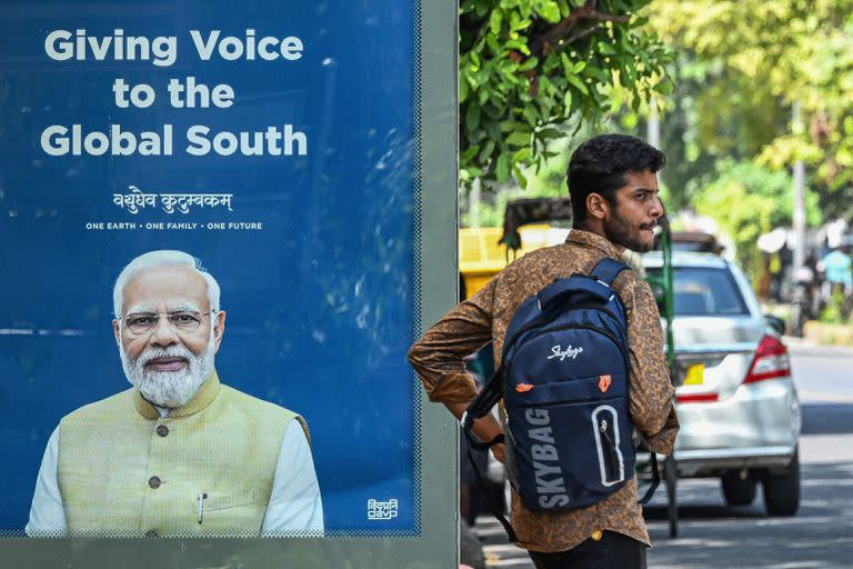 Un peatón espera junto a una parada de autobús que muestra el retrato del primer ministro de India, Narendra Modi, en Nueva Delhi el 4 de septiembre de 2023. 