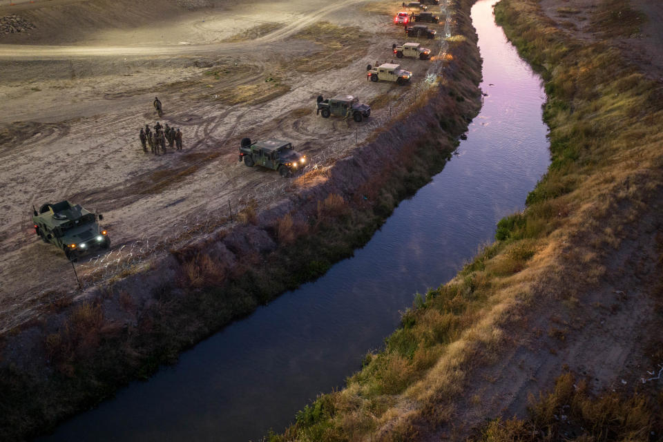 An aerial view of Texas National Guard troops and state troopers with their vehicles lining the bank of the Rio Grande, facing Mexico.