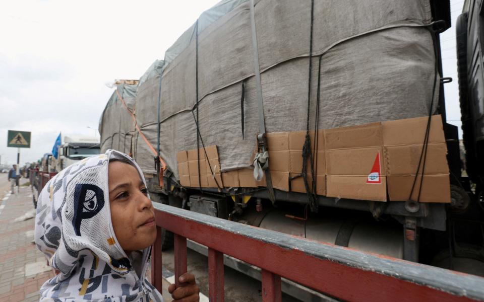 A child looks at trucks carrying aid waiting to head towards north Gaza during a temporary truce between Hamas and in Israel