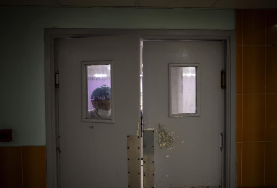 A Palestinian doctor wearing protective clothing walks out of the emergency room of the al-Quds Hospital in Gaza City, Monday, Sept. 7, 2020. Dozens of front-line health care workers have been infected, dealing a new blow to overburdened hospitals. (AP Photo/Khalil Hamra)