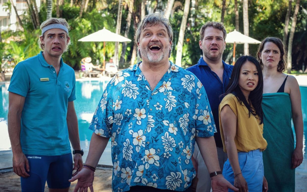 Edwin Öttel (Hape Kerkeling, zweiter von links) ist zurück: In der Miniserie "Club Las Piranjas" (RTL+) versucht er, die Hochzeit seines Sohnes Björn (Ben Münchow, dritter von rechts) und dessen Freundin Lani (Trang Le Hong, zweite von rechts) zu verhindern. Verägerte Hotelgäste (Isabell Polak) und überfordertes Personal (Campbell Caspary) sind da allenfalls Kollateralschäden.  (Bild: RTL / Ravi Gajjar / African Photo Productions)