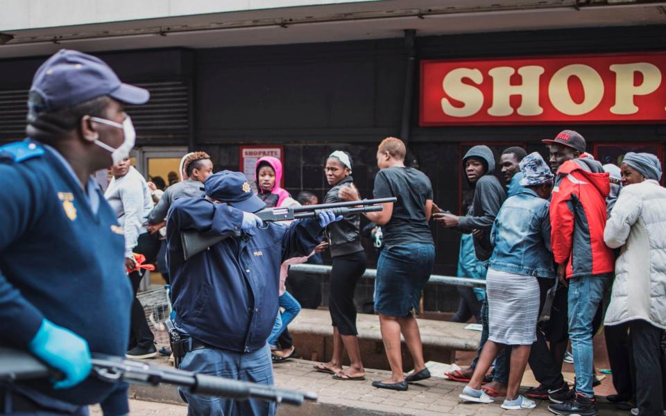 A South African policeman points his pump rifle to disperse a crowd of shoppers in Yeoville, Johannesburg -  MARCO LONGARI/AFP