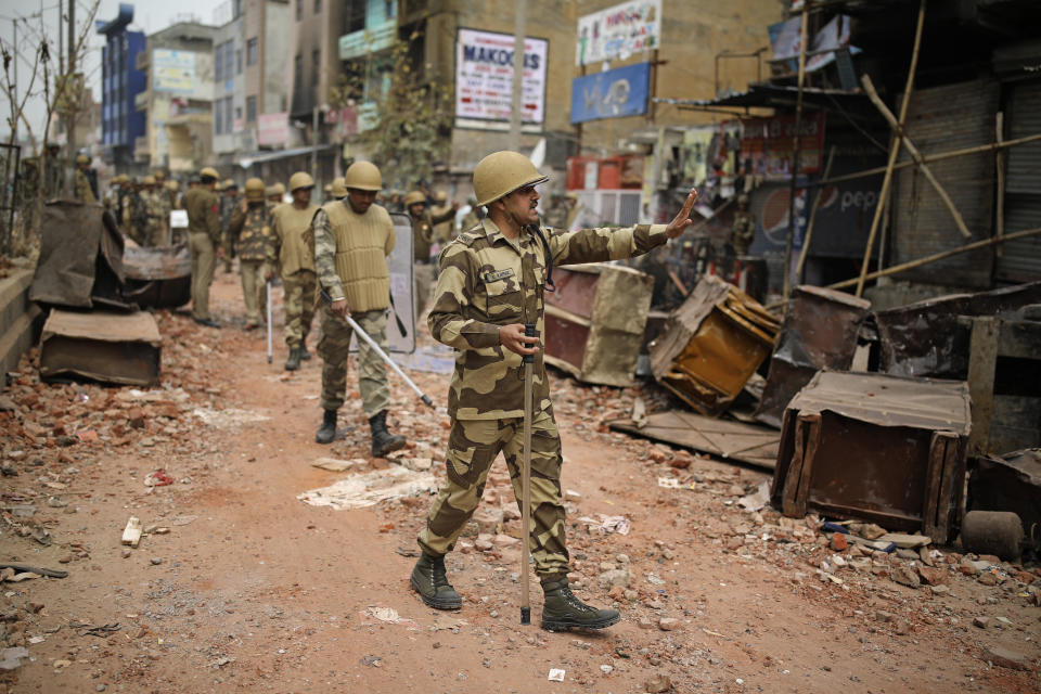 An Indian paramilitary soldier asks residents to stay indoors as they patrol a street vandalized in Tuesday's violence in New Delhi, India, Thursday, Feb. 27, 2020. India accused a U.S. government commission of politicizing communal violence in New Delhi that killed at least 30 people and injured more than 200 as President Donald Trump was visiting the country. The violent clashes between Hindu and Muslim mobs were the capital's worst communal riots in decades and saw shops, Muslim shrines and public vehicles go up in flames. (AP Photo/Altaf Qadri)