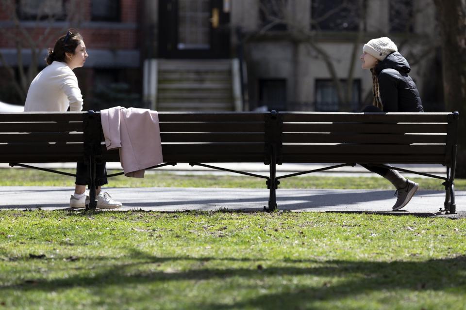 Two women practice social distancing while talking on Commonwealth Avenue Mall in Boston during the coronavirus outbreak Saturday, April 4, 2020. (AP Photo/Michael Dwyer)