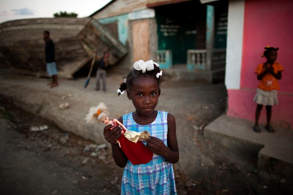 Claudine holds a Barbie doll next to the port in Port-du-Paix, Haiti, Thursday, Jan. 27, 2011.