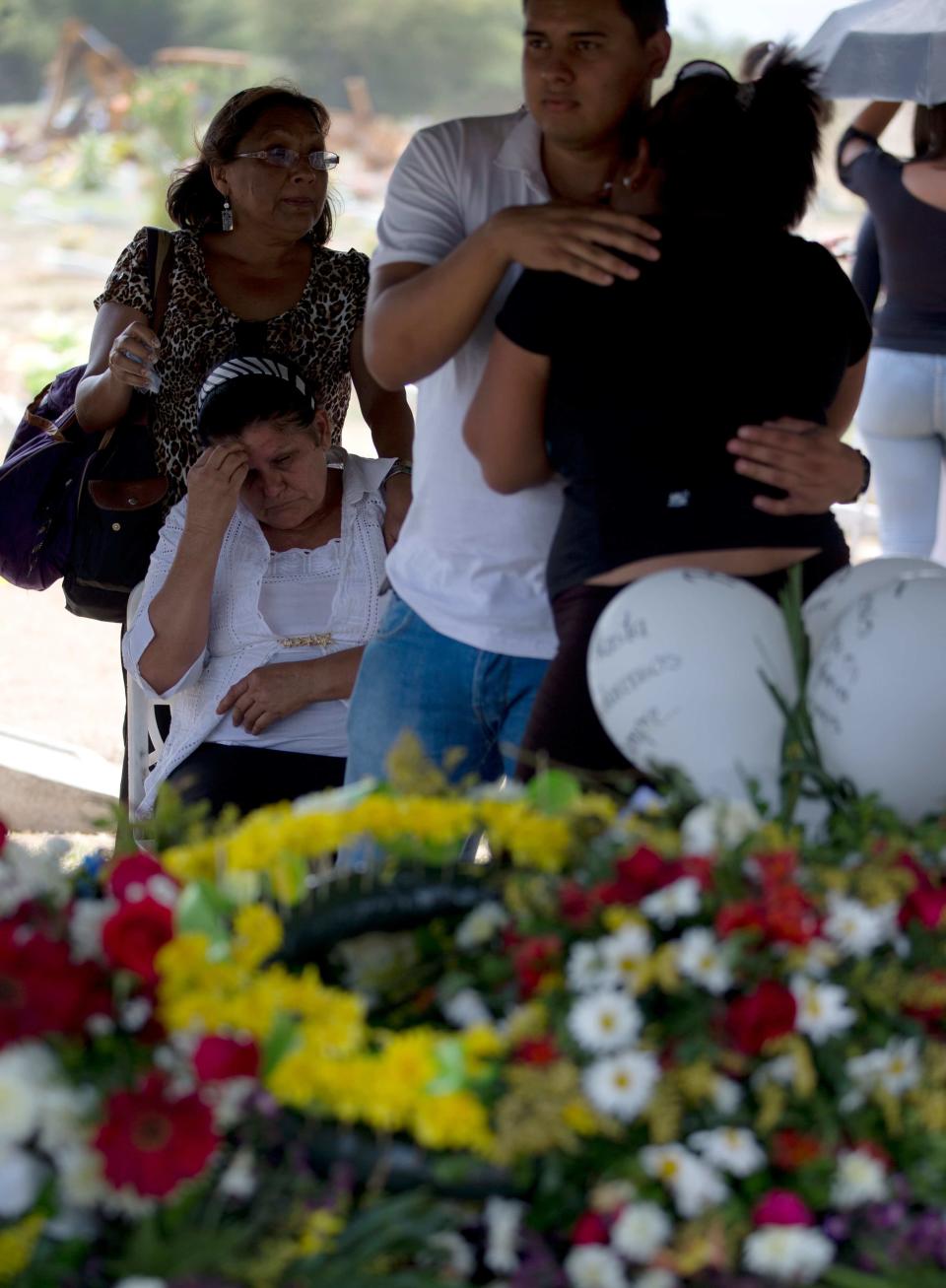 In this photo taken on Friday, March 14, 2014. Relatives of University student Jesus Enrique Acosta cry next to his tomb during his funeral grave in Valencia, Venezuela. The people of the poor district of La Isabelica were made to pay for taking to the streets in anti-government protests. More than a dozen masked men on motorcycles roared through, shooting up a barricade and killing a university student and a 42-year-old man painting his house. (AP Photo/Fernando Llano)