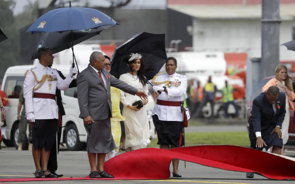 Meghan, Duchess of Sussex waits as Fiji Prime Minister Frank Bainimarama, left, gestures as a red carpet is laid during the official welcome ceremony in Suva, Fiji, Tuesday, Oct. 23, 2018. Britain's Prince Harry and his wife Meghan are on day eight of their 16-day tour of Australia and the South Pacific.(AP Photo/Kirsty Wigglesworth,Pool)