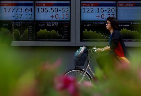 A woman cycles past a display of foreign exchange rates including the dollar to yen rate in Tokyo, Japan, May 2, 2016. REUTERS/Thomas Peter