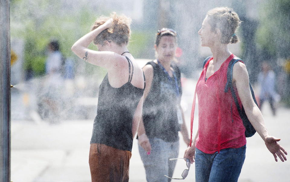 People use misters to cool down during a heatwave in Montreal, on July 2, 2018. Montreal's mayor is unveiling the city's plan to respond to heatwaves after dozens of people died amid high temperatures last summer. (THE CANADIAN PRESS/Graham Hughes)