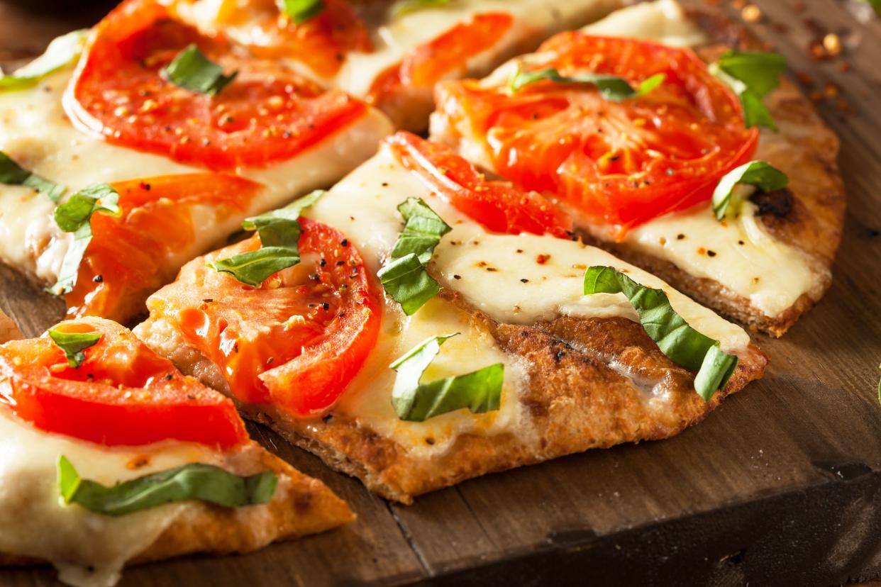 Closeup of 15 minute easy margherita flatbread pizza pieces on a wooden cutting board