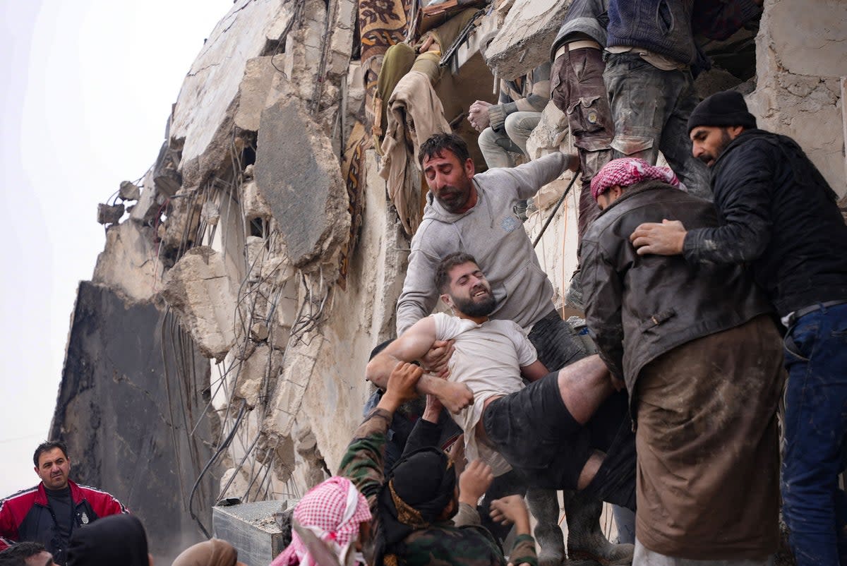 Residents retrieve an injured man from the rubble of a collapsed building following an earthquake in the town of Jandaris, in the countryside of Syria's northwestern city of Afrin (AFP via Getty Images)