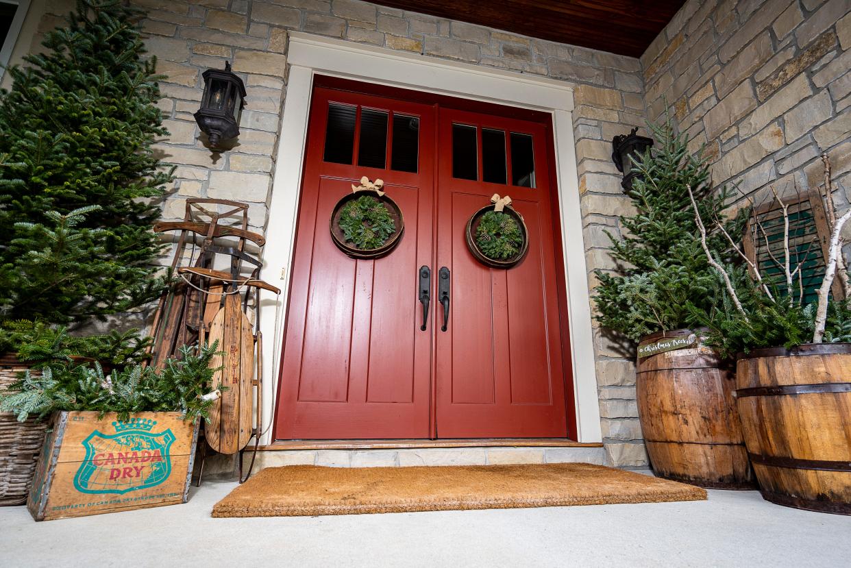 The entrance to Julie Hunt's home is decorated with antique barrels, sleds and wreaths made from sifters.