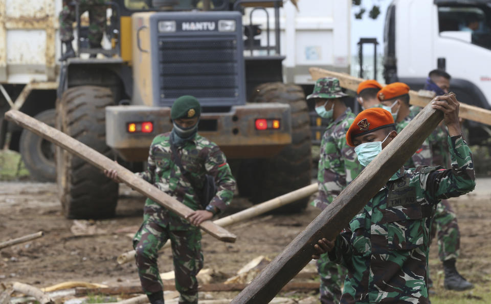 Soldiers remove debris from a damaged house in the tsunami-hit village of Carita, Indonesia, Friday, Dec. 28, 2018. Indonesia has widened the no-go zone around an island volcano that triggered a tsunami on the weekend, killing hundreds of people in Sumatra and Java. (AP Photo/Achmad Ibrahim)
