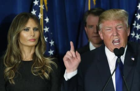 Republican U.S. presidential candidate Donald Trump gestures during his victory speech as his wife Melania, looks on at his 2016 New Hampshire presidential primary night rally in Manchester, New Hampshire February 9, 2016. REUTERS/Jim Bourg