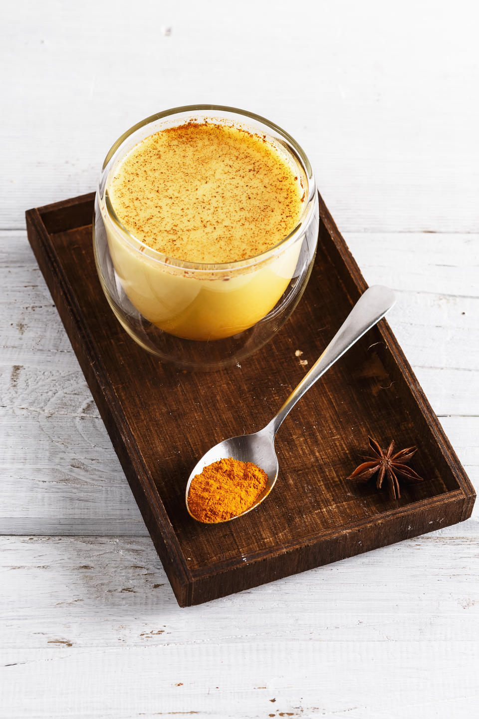 Close up image of golden latte in a wooden box over white wooden table