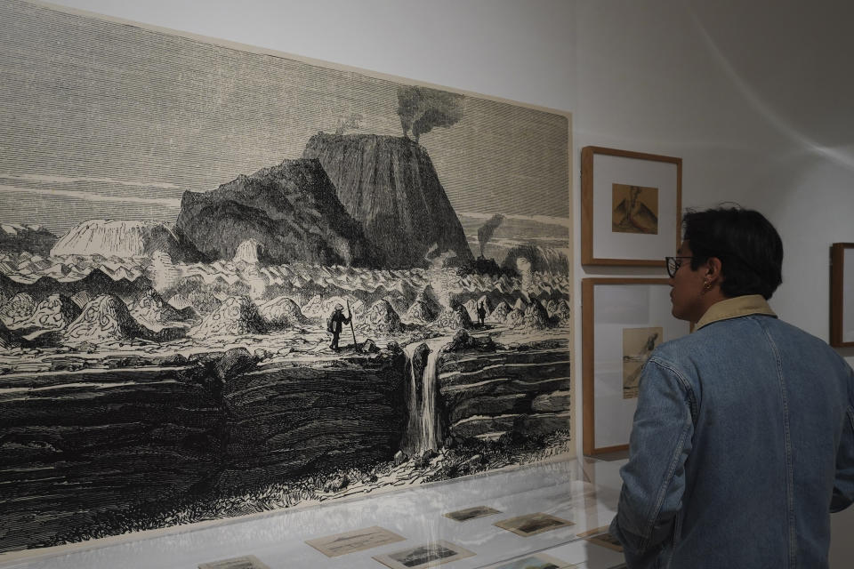 Un visitante mira una ilustración de Alexander von Humboldt en la exposición recientemente inaugurada que el Museo de Arte Moderno reunió sobre los volcanes, el paisaje que crean y su influencia en la cultura mexicana, en la Ciudad de México, el sábado 12 de agosto de 2023. (Foto AP/Marco Ugarte)