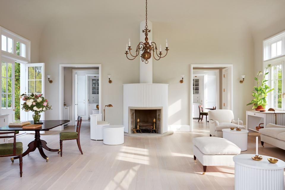 The main room is painted a Benjamin Moore gray; 19th-century brass chandelier, regency table and chairs, and Guillot-designed fluted fireplace and matching furniture.