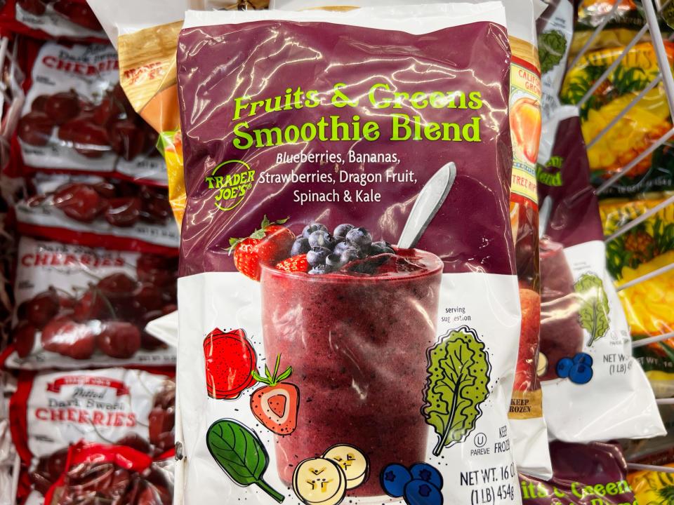 A white and purple bag of Trader Joe's fruits and greens smoothie blend with illustrations of spinach, bananas, blueberries, and strawberries on it