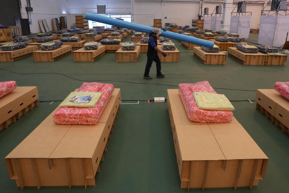 A worker carries a pipe while preparing a field hospital set up inside a cargo building in Don Mueang International Airport in Bangkok, Thailand, Thursday, July 29, 2021. Health authorities raced on Thursday to set up yet another large field hospital in Thailand's capital as the country recorded a new high in COVID-19 cases and deaths. The hospital, one of many already in use, was being set up at one of Bangkok's two international airports after the capital ran out of hospital beds for thousands of infected residents. (AP Photo/Sakchai Lalit)