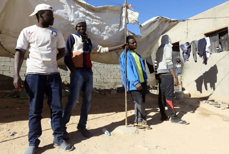 African migrants stand under the sun at a shelter in the town of Bani Walid, on the edge of the desert southeast of the Libyan capital Tripoli