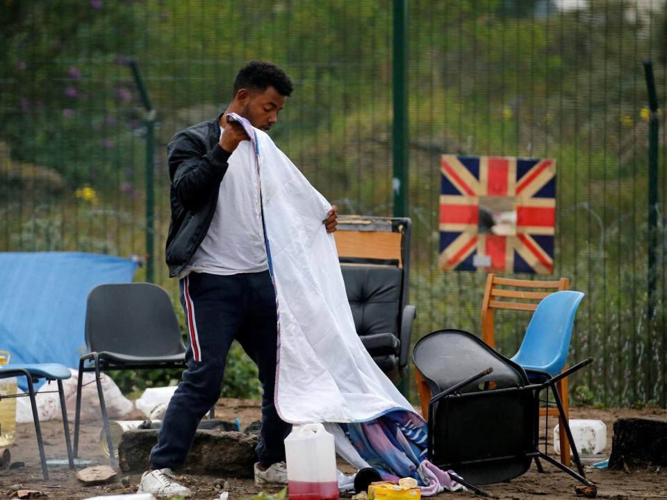 A man packs his belongings as police officers clear a refugee camp in Calais, France: REUTERS