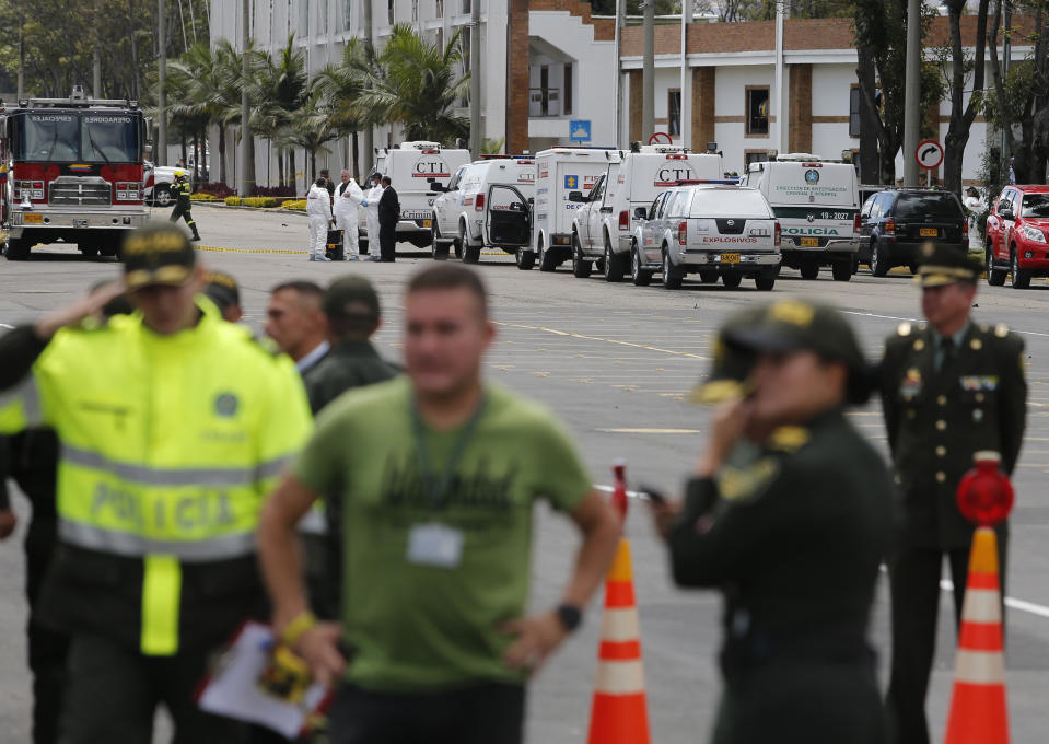 Forensic workers, behind top, work the scene of a deadly car bombing at the General Santander police academy in Bogota, Colombia, Thursday, Jan. 17, 2019. (AP Photo/John Wilson Vizcaino)