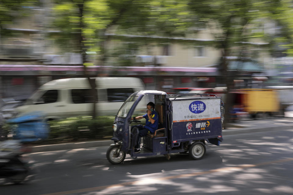 A private delivery company's courier wearing a protective face mask to help curb the spread of the new coronavirus rides his delivery cart passes by a residential area in Beijing, Sunday, June 21, 2020. According to state media reports, nearly one hundred thousand delivery workers have to accept the nucleic acid testing, a countermeasure to prevent the spread of the virus in the capital city. (AP Photo/Andy Wong)