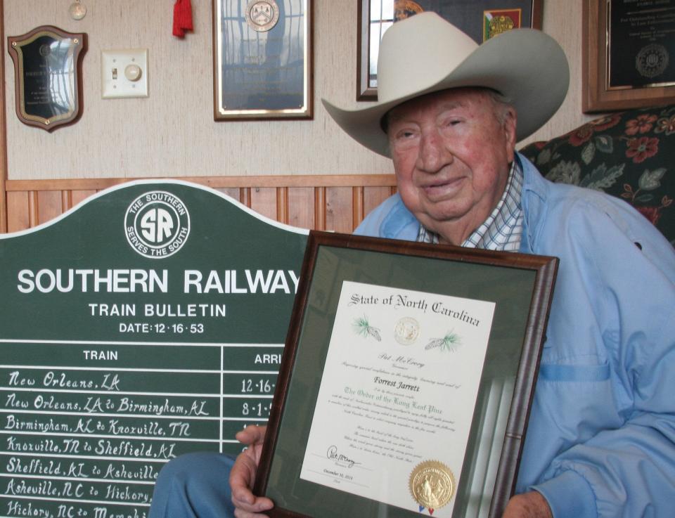 Forrest Jarrett displays his Order of the Long Leaf Pine proclamation in the railroad room at his home in Leicester.