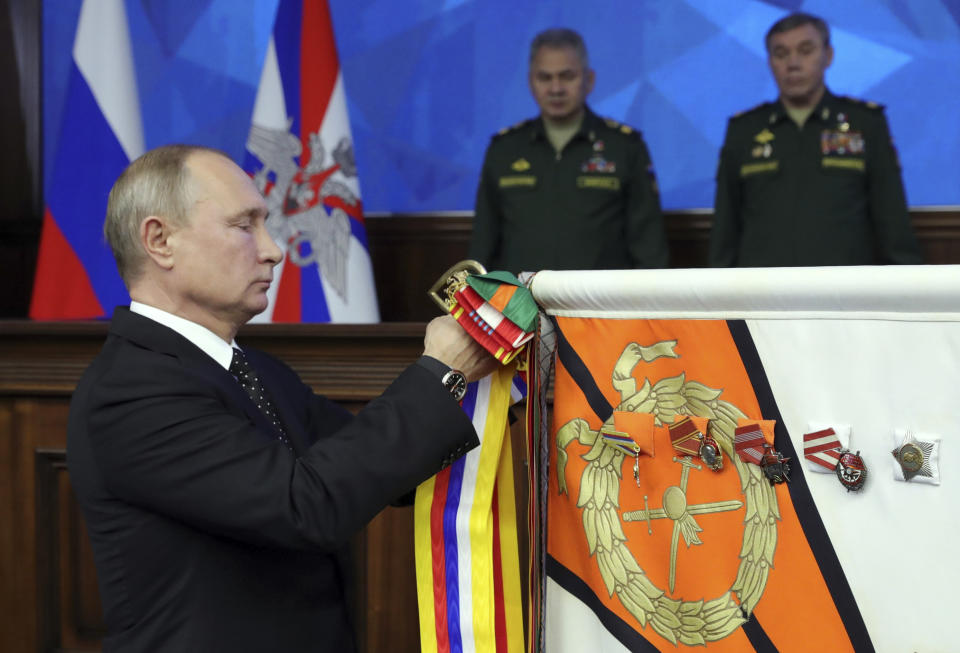 Russian President Vladimir Putin, left, pins a medal on a military banner during a meeting with the top military staff in the Russian Defense Ministry's headquarters in Moscow, Russia, Tuesday, Dec. 18, 2018. Putin said that new Russian weapons have no foreign equivalents, helping ensure the nation's security for decades to come. (Mikhail Klimentyev, Sputnik, Kremlin Pool Photo via AP)
