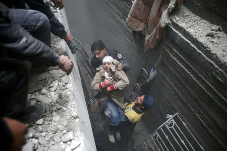 Syria Civil Defence members help an unconscious woman from a shelter in the besieged town of Douma, Eastern Ghouta, Damascus, Syria February 22, 2018. REUTERS/Bassam Khabieh