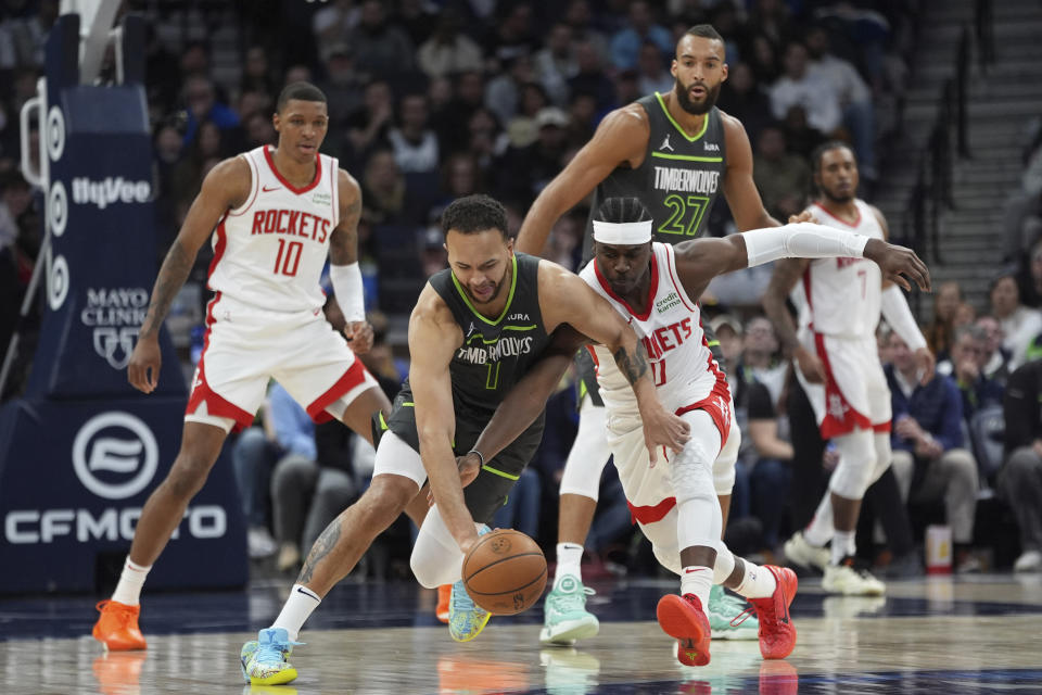 Minnesota Timberwolves forward Kyle Anderson, left, and Houston Rockets guard Aaron Holiday compete for possession during the first half of an NBA basketball game Tuesday, April 2, 2024, in Minneapolis. (AP Photo/Abbie Parr)