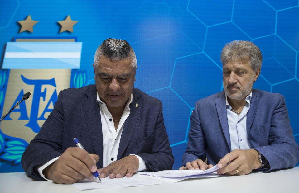General Secretary of the Argentina's Footballers' Union (FAA) Sergio Marchi, right, Claudio Tapia, president of Argentina's Soccer Federation, left, sign the contract to implement a plan to professionalize women's soccer in Buenos Aires, Argentina, Saturday, March 16, 2019. Almost 90 years after men's soccer turned professional in Argentina, the women's game is still being played by amateur athletes who get little to no money for their work on the field. (AP Photo/Daniel Jayo)