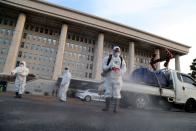 Employees from a disinfection service company sanitize outside the National Assembly in Seoul