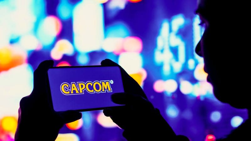 Someone is holding a phone with the Capcom label against a purple background emblazoned on the screen.