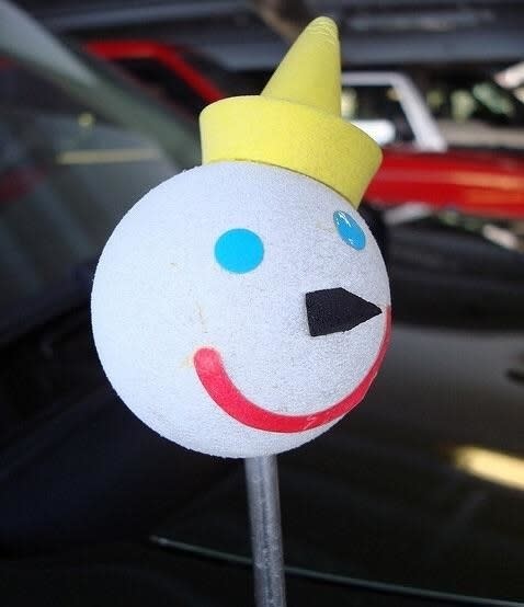 Handmade car antenna topper resembling a snowman face with a yellow cone hat