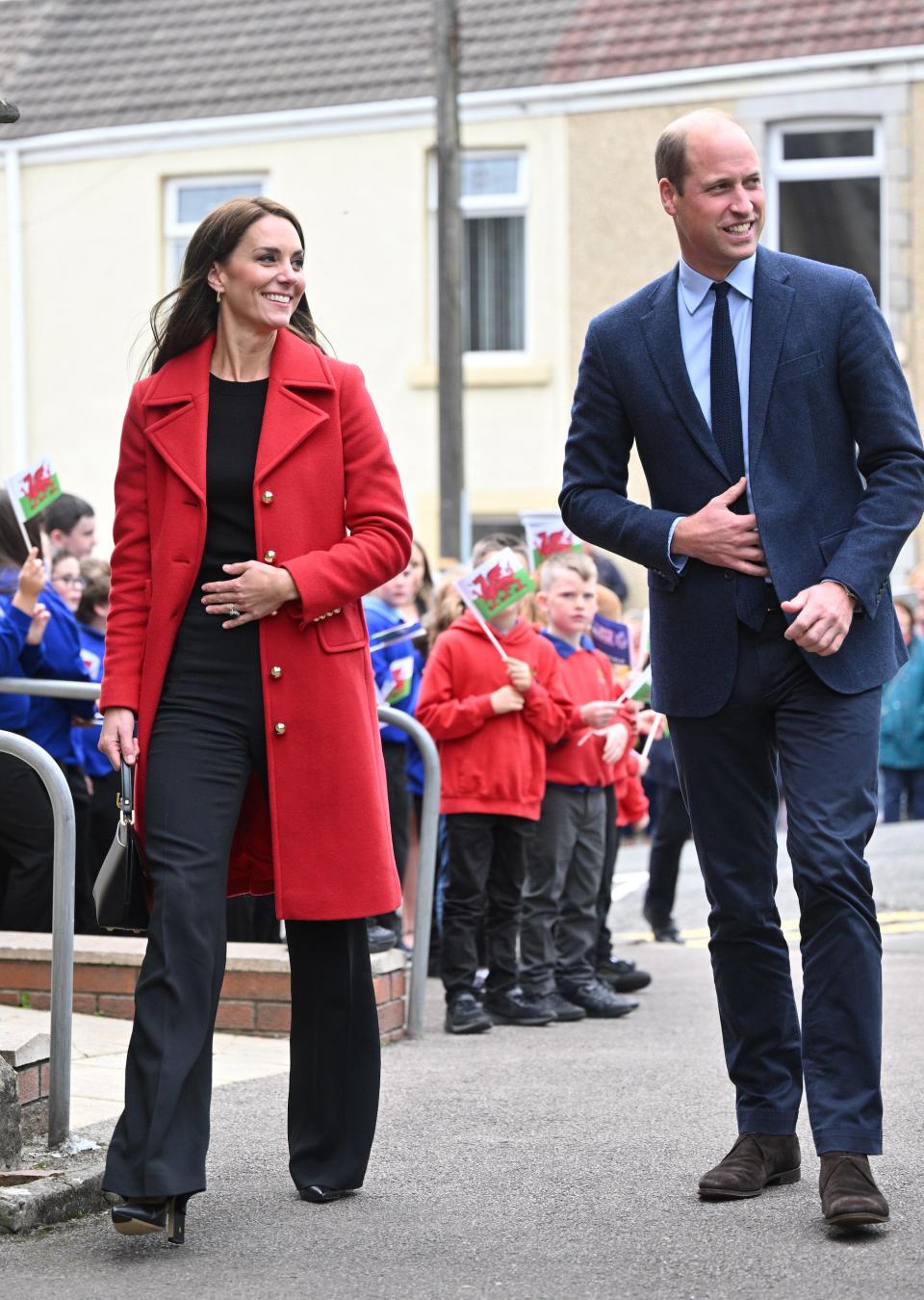 Kate Middleton and Prince William walk down a street.