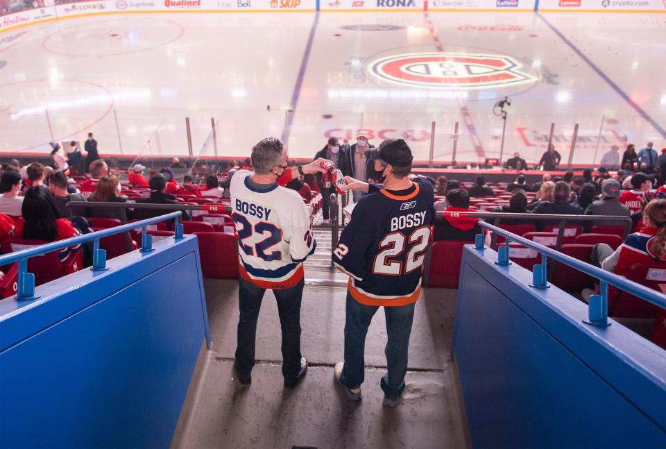 Mike Bossy fans say cheers touching beers together prior to an NHL hockey game between the Montreal Canadiens and the New York Islanders in Montreal, Friday, April 15, 2022. Hockey Hall of Famer Bossy died Thursday night of lung cancer. He was 65. (Graham Hughes/The Canadian Press via AP)