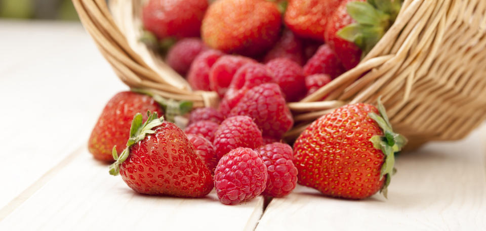 raspberry and strawberries in a basket on the table in the garden