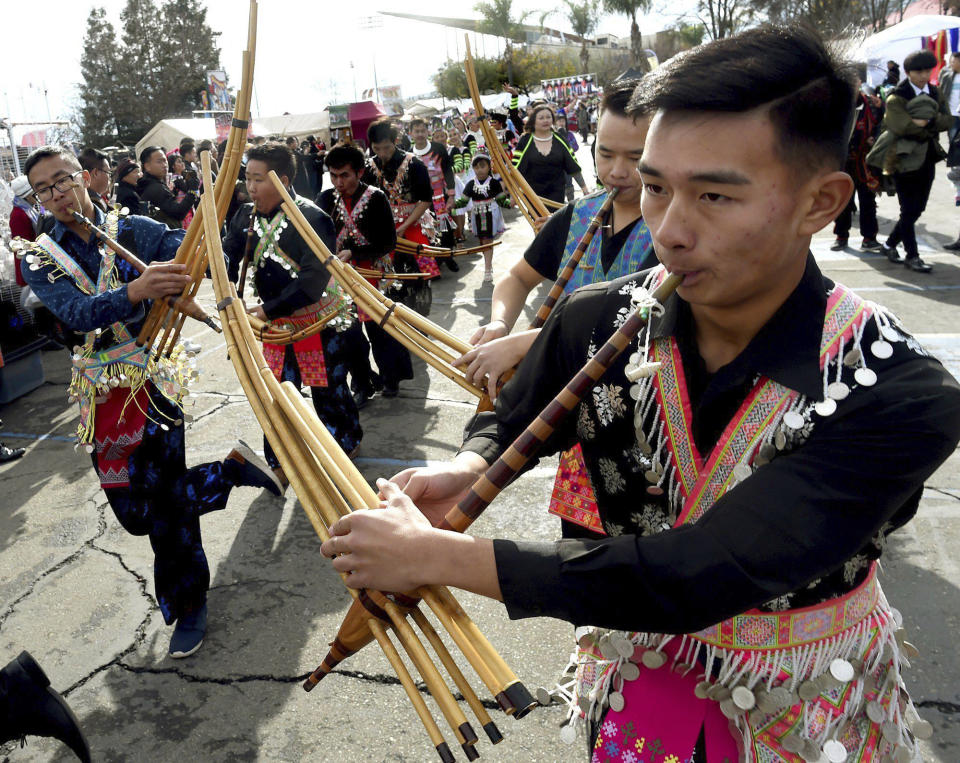 David Vue, right, and others perform with the qeej, a traditional bamboo flute, during the parade kicking off the first day of the Hmong New Year celebration at the Fresno Fairgrounds, Thursday Dec. 26, 2019. (John Walker/The Fresno Bee via AP)