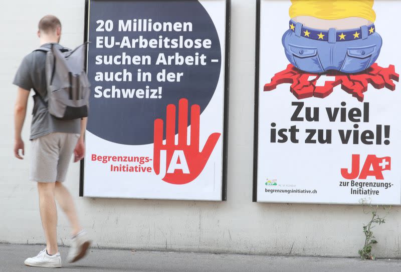 FILE PHOTO: Man walks past posters against the anti-immigration initiative in Zurich