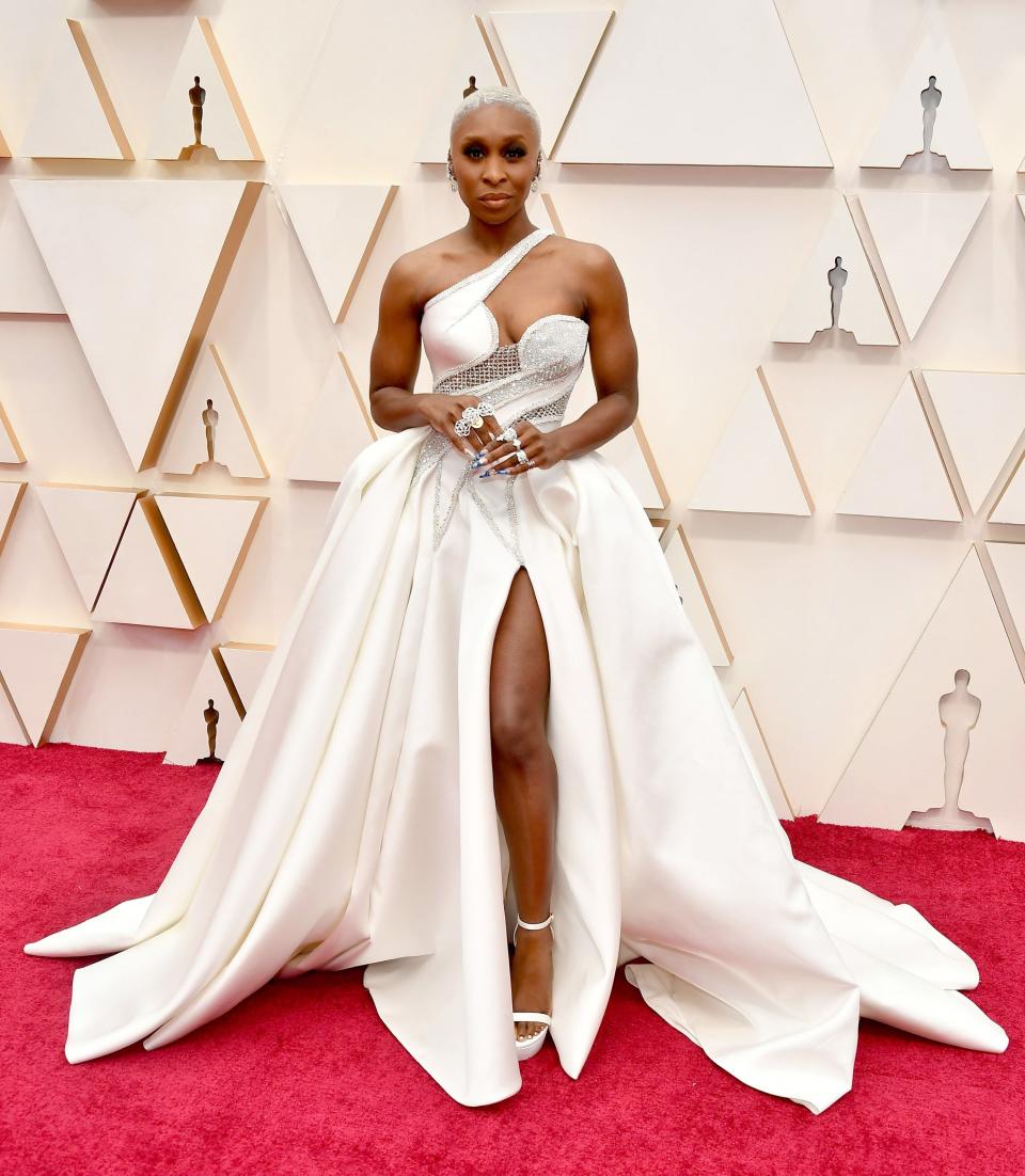 Cynthia wearing a huge white gown with a slit