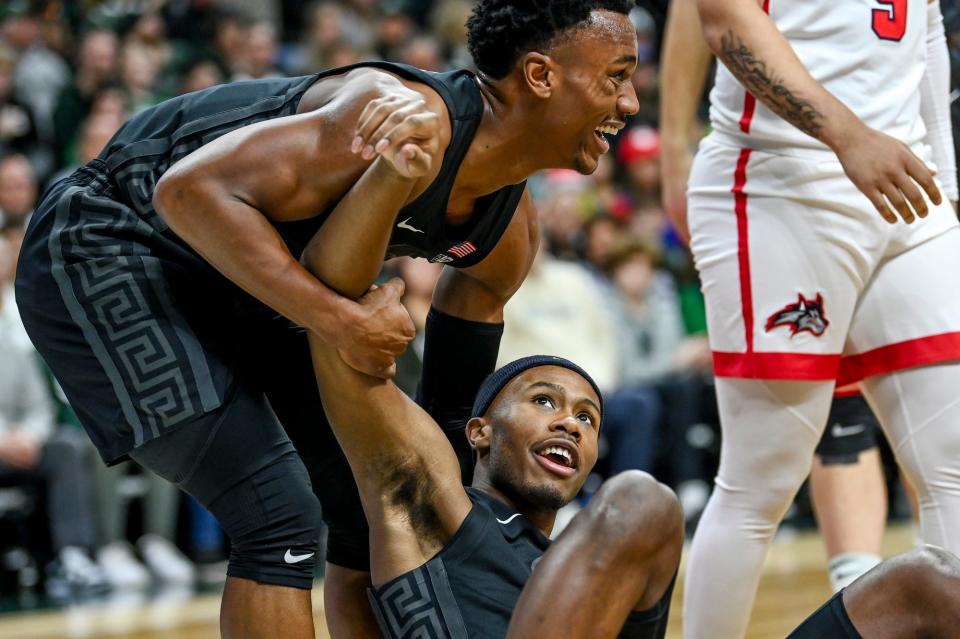 Michigan State's Tyson Walker, left, helps up Tre Holloman after he was fouled during the first half in the game against Stony Brook on Thursday, Dec. 21, 2023, at the Breslin Center in East Lansing.