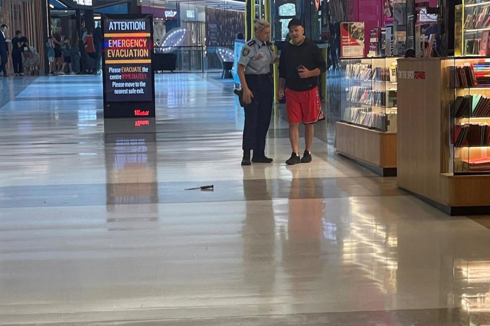 PHOTO: A police officer talks to an eyewitness as a knife used by an attacker lies on the floor, in Westfield Bondi Junction shopping center, in Sydney, Australia, on April 13, 2024, in this picture obtained by Reuters.  (Ugc via Reuters)
