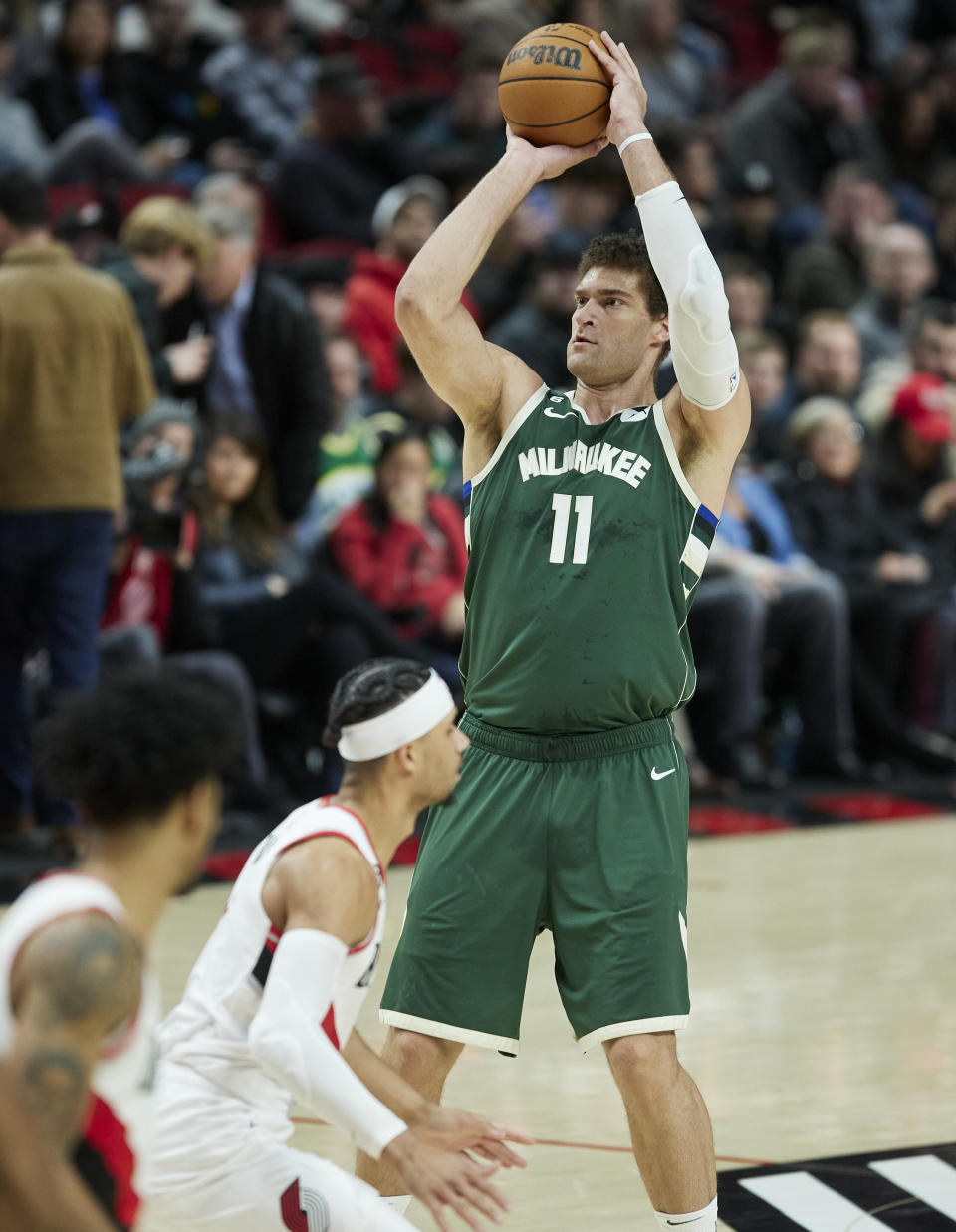 Milwaukee Bucks center Brook Lopez (11) shoots a 3-point basket over Portland Trail Blazers guard Josh Hart during the second half of an NBA basketball game in Portland, Ore., Monday, Feb. 6, 2023. (AP Photo/Craig Mitchelldyer)