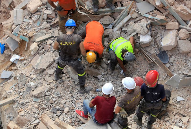 Rescue team members search through rubble of buildings damaged due to the massive explosion in Beirut